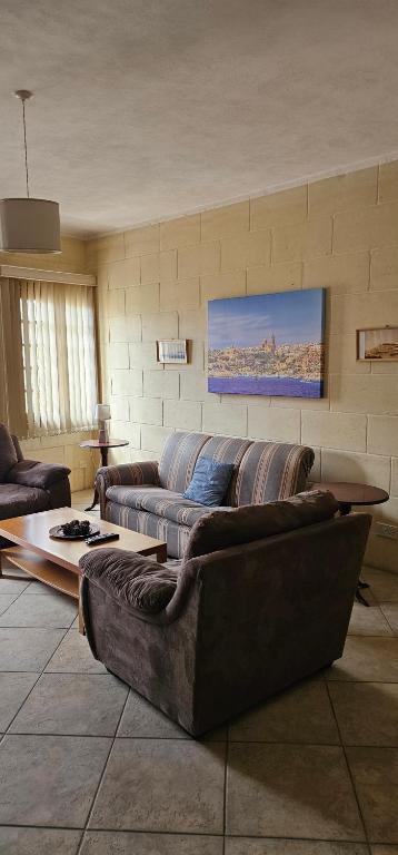 a living room with a couch and a table at Quiet, spacious 3 bedroom 2 bathroom apartment in Għajnsielem