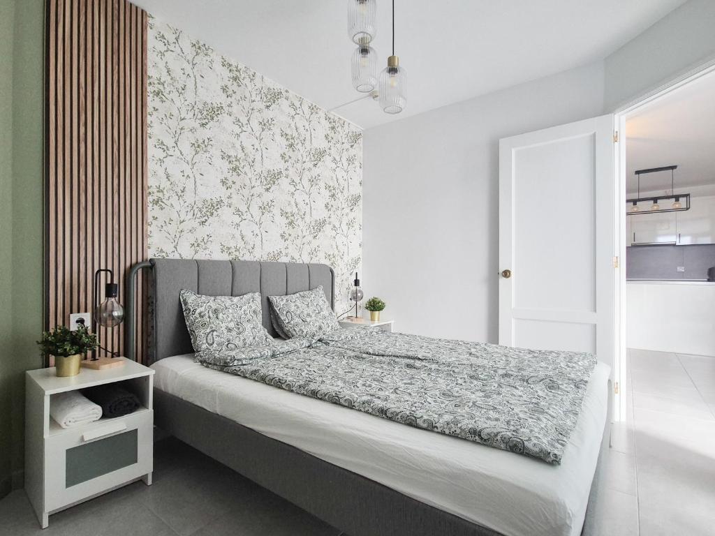 a bedroom with a bed with a gray headboard at ELKO Apartman in Mogán