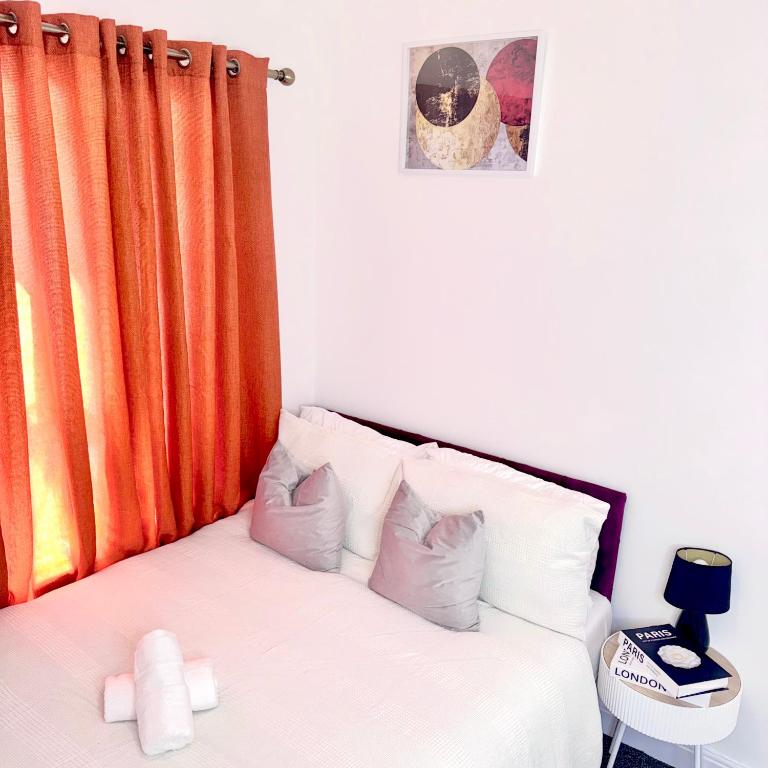 a bedroom with a white bed with an orange curtain at Bright Housing in Gateshead