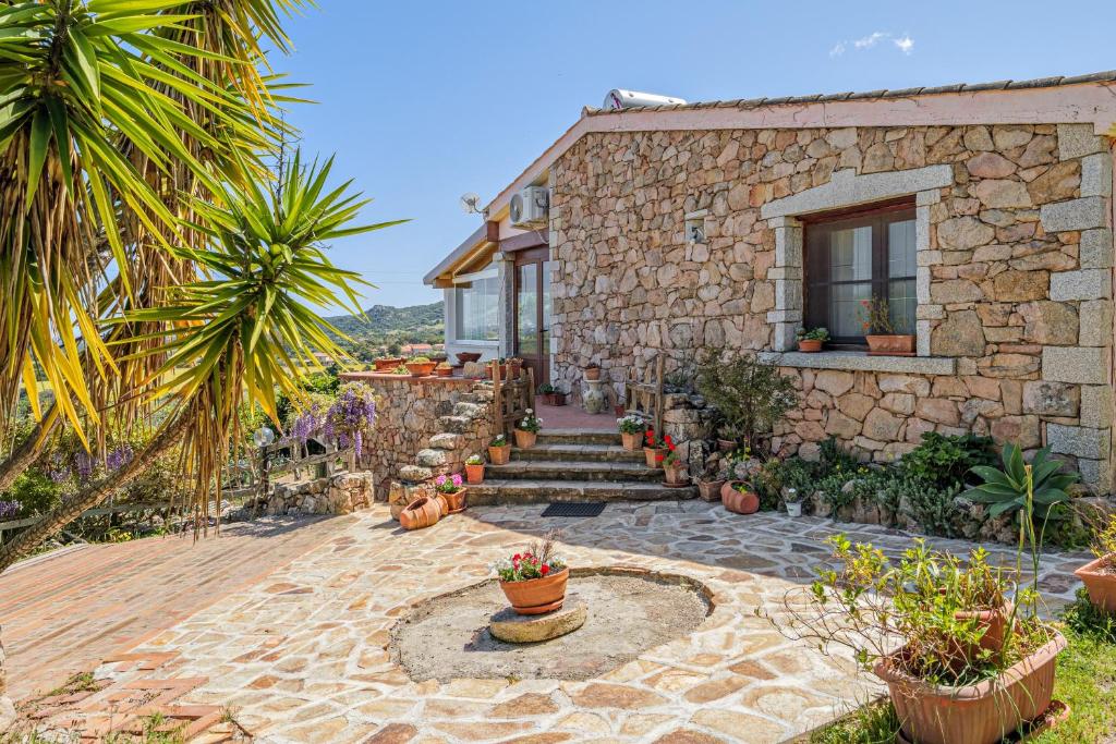 a stone house with a courtyard with potted plants at Villa Montalmutu con vista mare in Nuragheddu