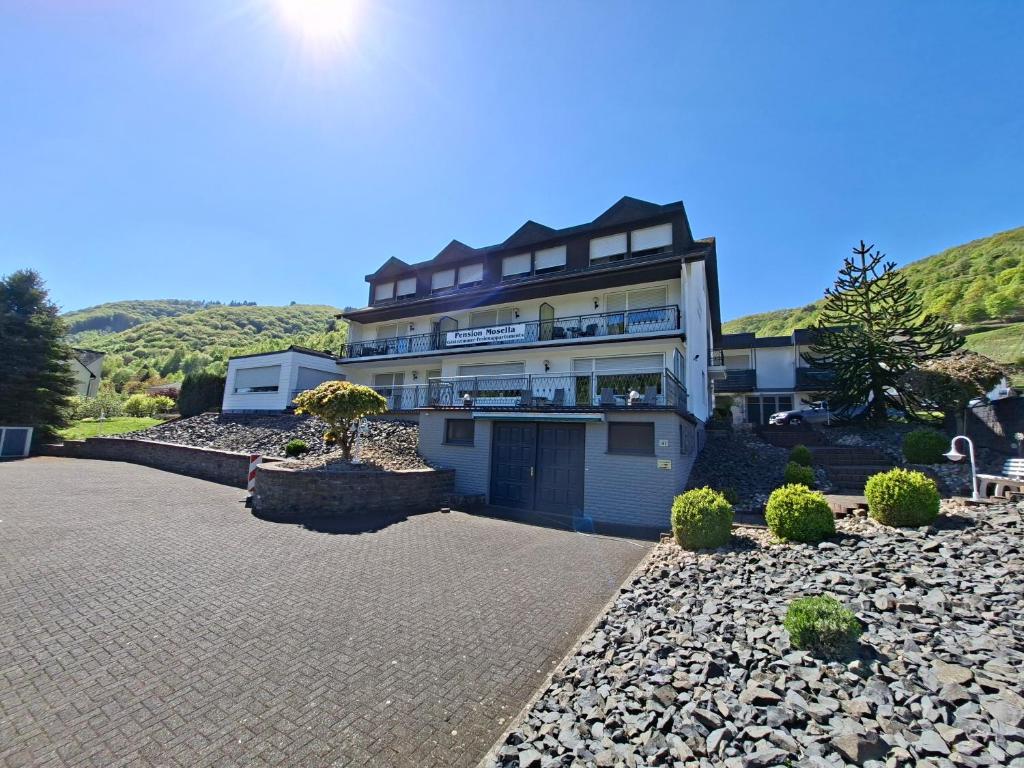 a large building with a driveway in front of it at Pension Mosella, Gästezimmer in Sankt Aldegund