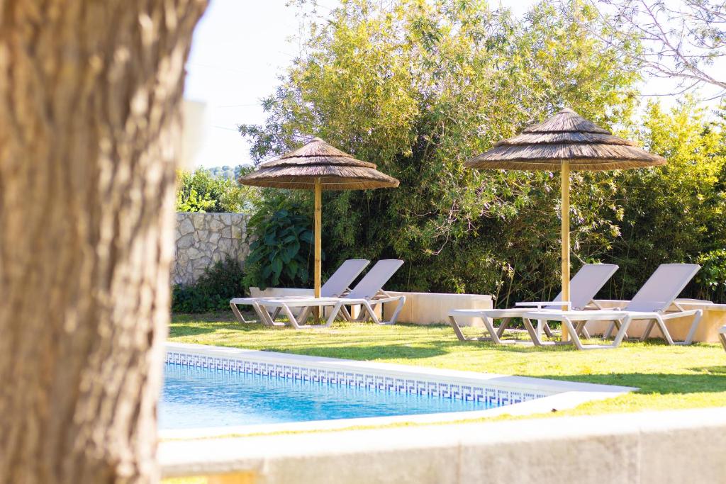 two umbrellas and lounge chairs next to a swimming pool at Quinta da Vala - Veranda Suite 1 in Porches