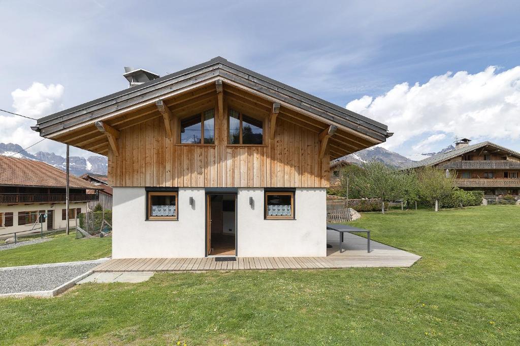 a house with a wooden roof on top of a field at Chalet Individuel - Saflalou in Combloux