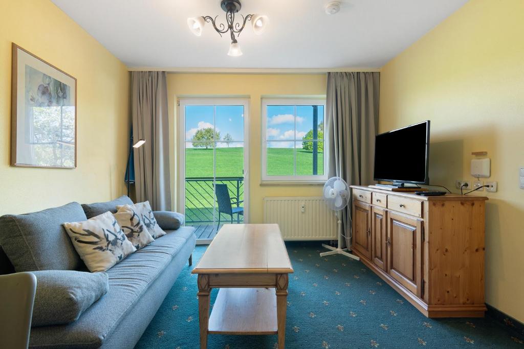 a living room with a couch and a tv at Apartment mit Gartenblick K1 106 in Spalt