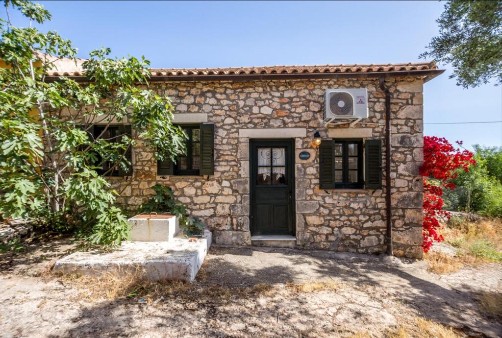 a stone house with a black door and a window at Stavlo Open Plan Cottage Zakynthos in Koríthion