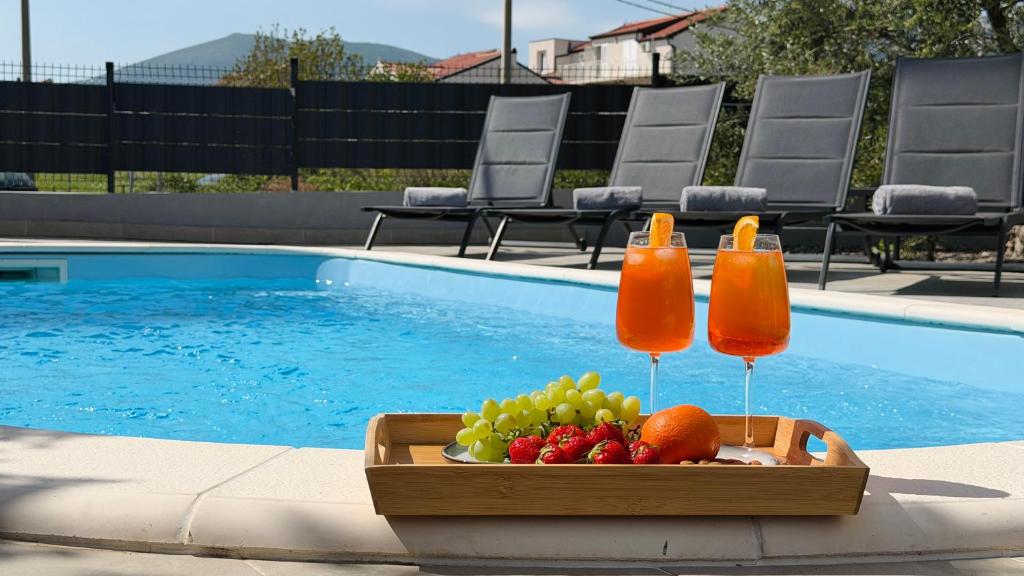 a tray of fruit and drinks next to a swimming pool at Moonlight Luxury Apartment with Private Pool and Parking in Kaštela
