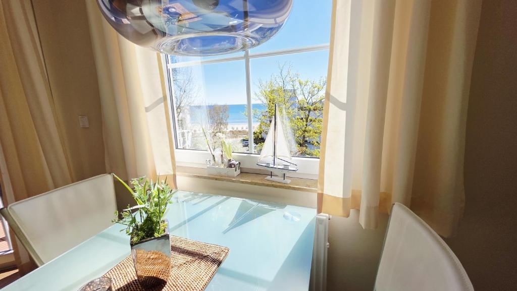 a dining room table with a window with a view of a sailboat at Residenz am Yachthafen 14 in Grömitz