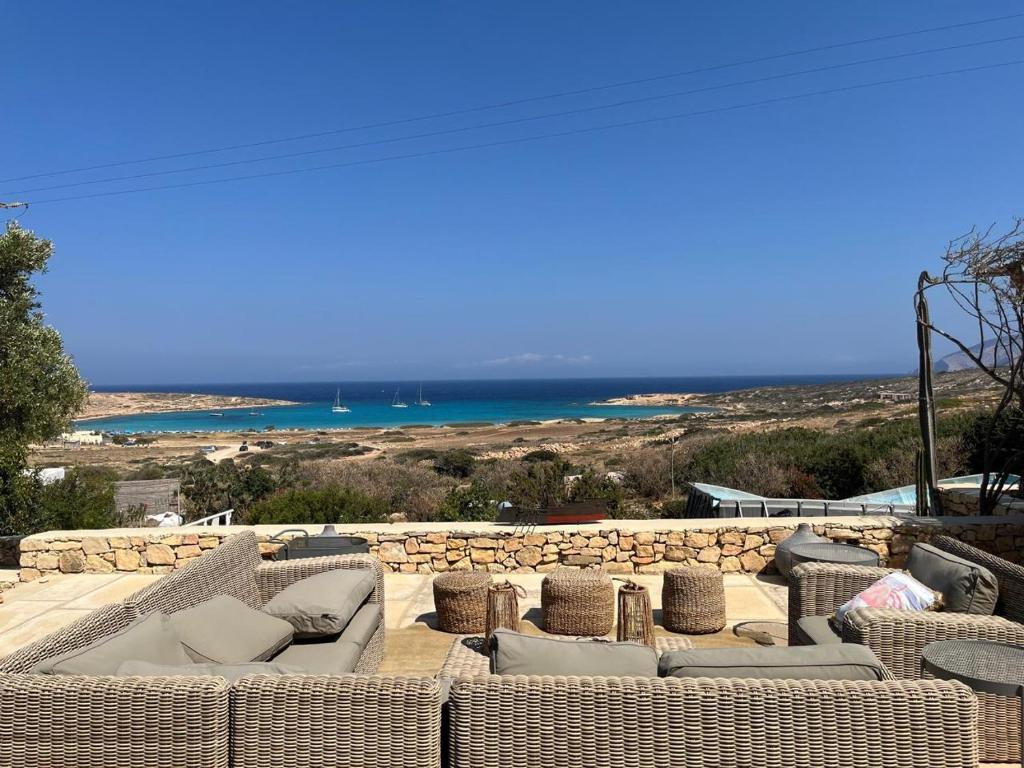 a group of wicker couches sitting on a patio with the ocean at Ellie Villa Seaside Koufonisi in Nisída Koufonísion