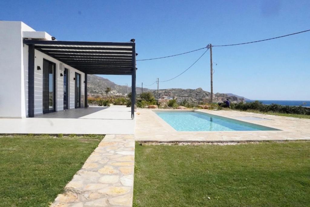 a house with a swimming pool next to the ocean at Villas By George in Afiartis