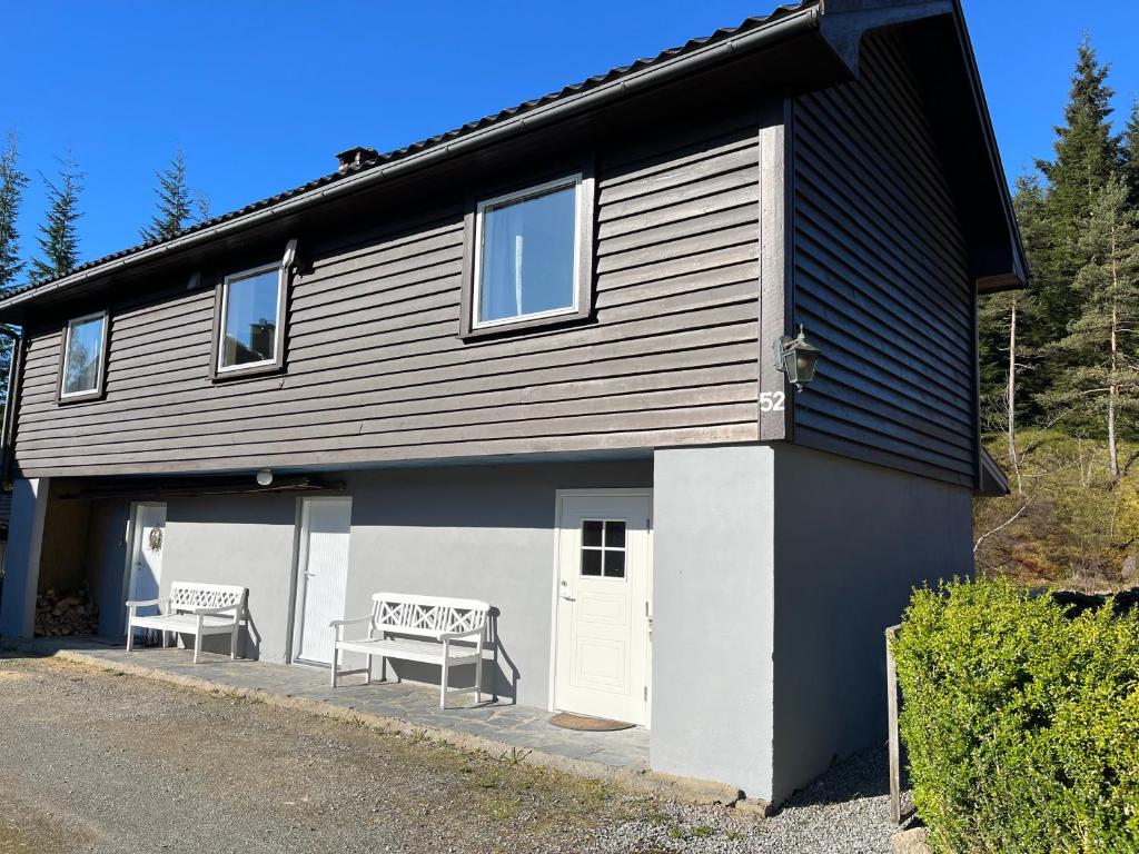 a house with two benches sitting outside of it at 2 bedroom apartment with beautiful view in Sauda