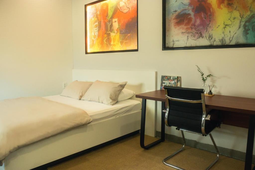 a bedroom with a desk and a bed and a chair at Fair Dinkum Stay District 1 in Ho Chi Minh City