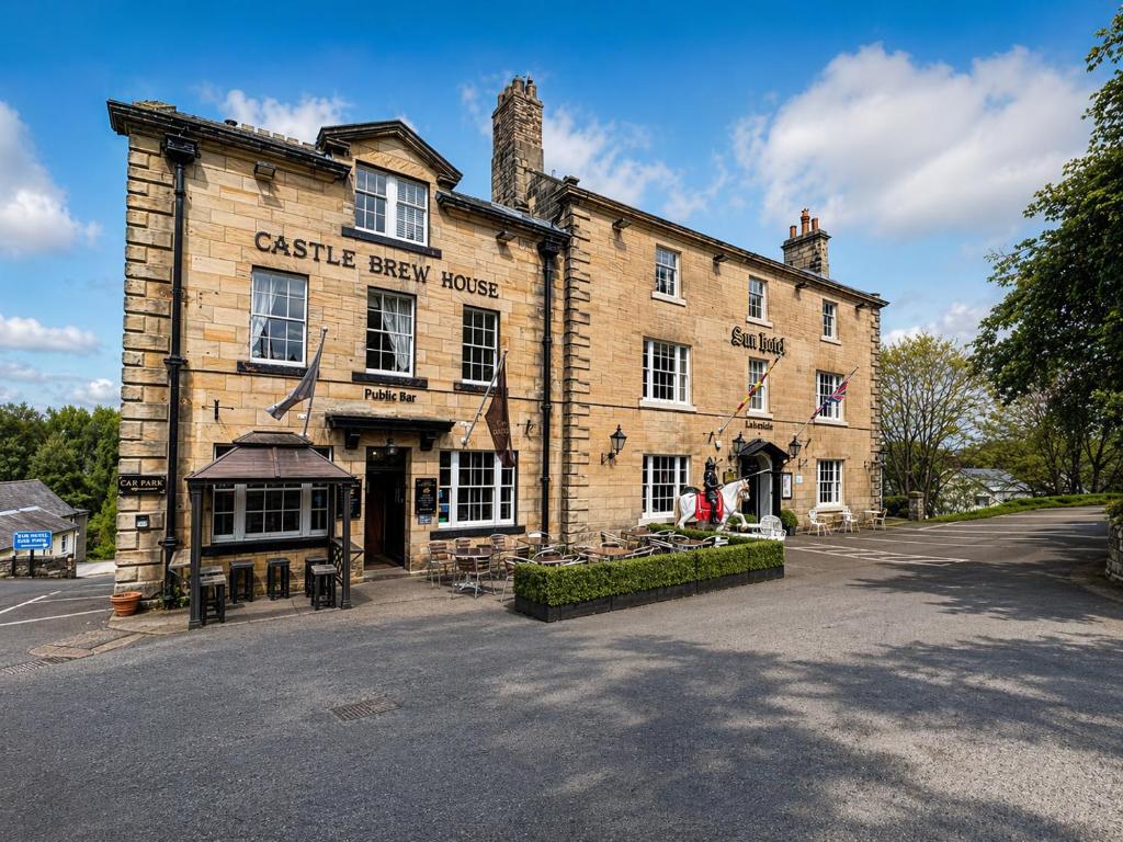 a large brick building with a castle east house at The Sun Hotel in Warkworth