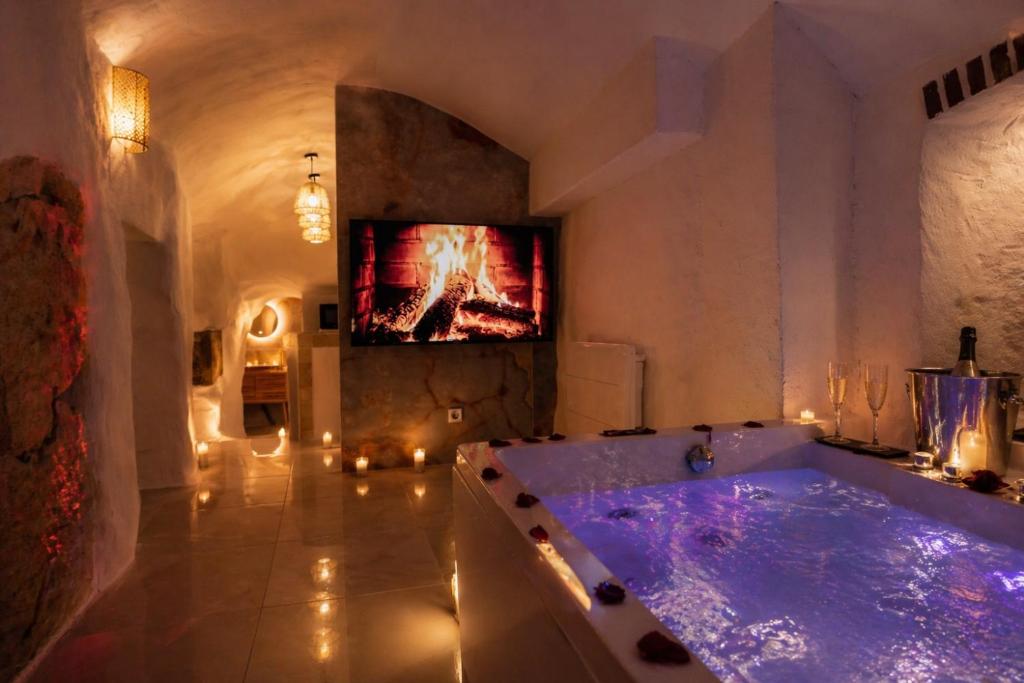 a large bathroom with a tub with a tv on the wall at Le temple d'Aphrodite, Appartement avec SPA in Vienne