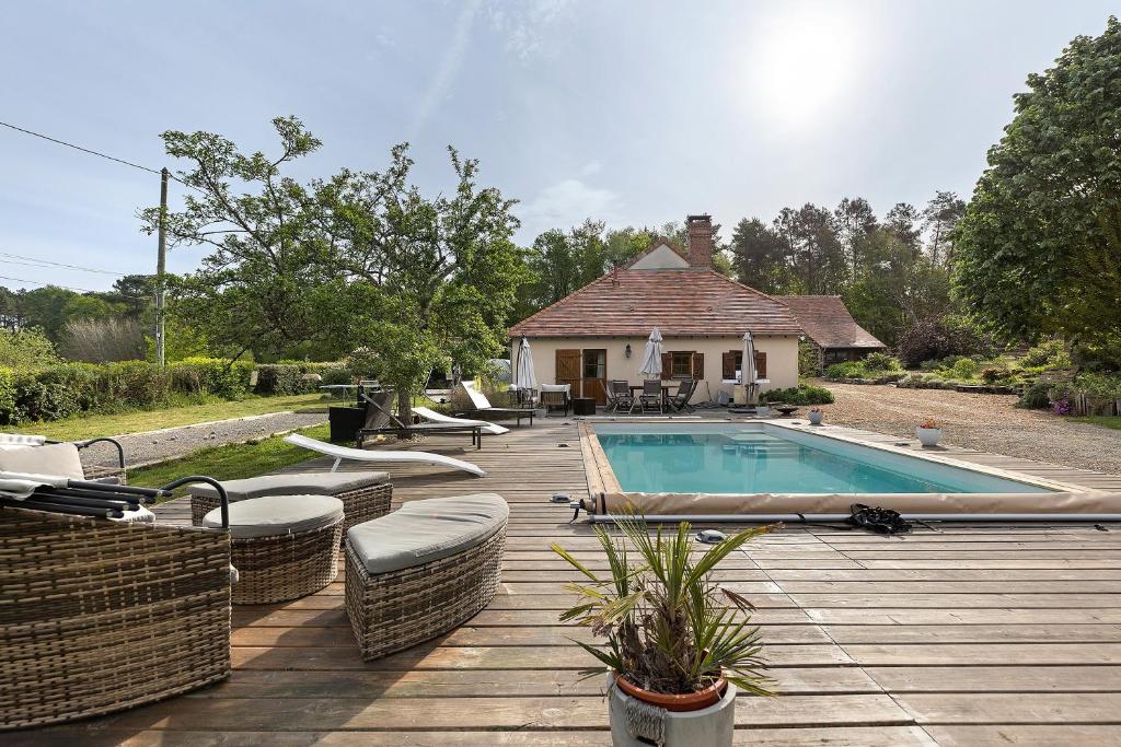 a wooden deck with a swimming pool and a house at La Lizardiere des Landes in La Flèche