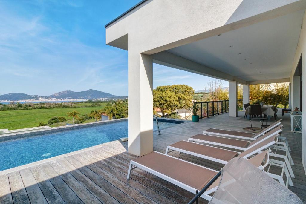an outdoor deck with chairs and a swimming pool at Stagnolo in Porticcio