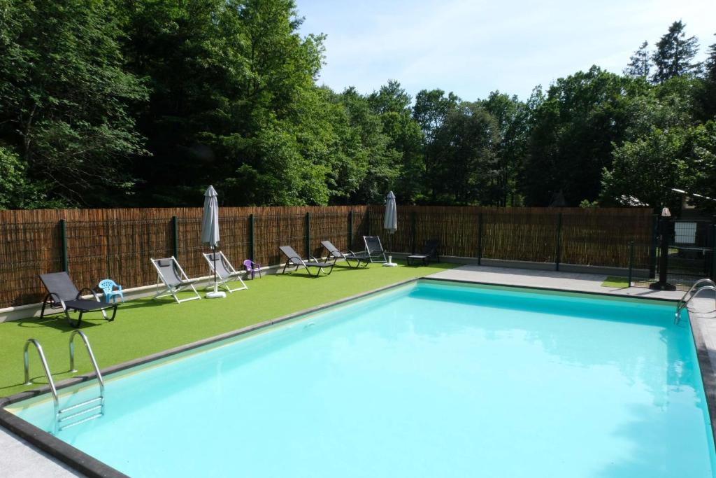 a swimming pool with lounge chairs and a fence at Gîte Des Houx in Le Soulié