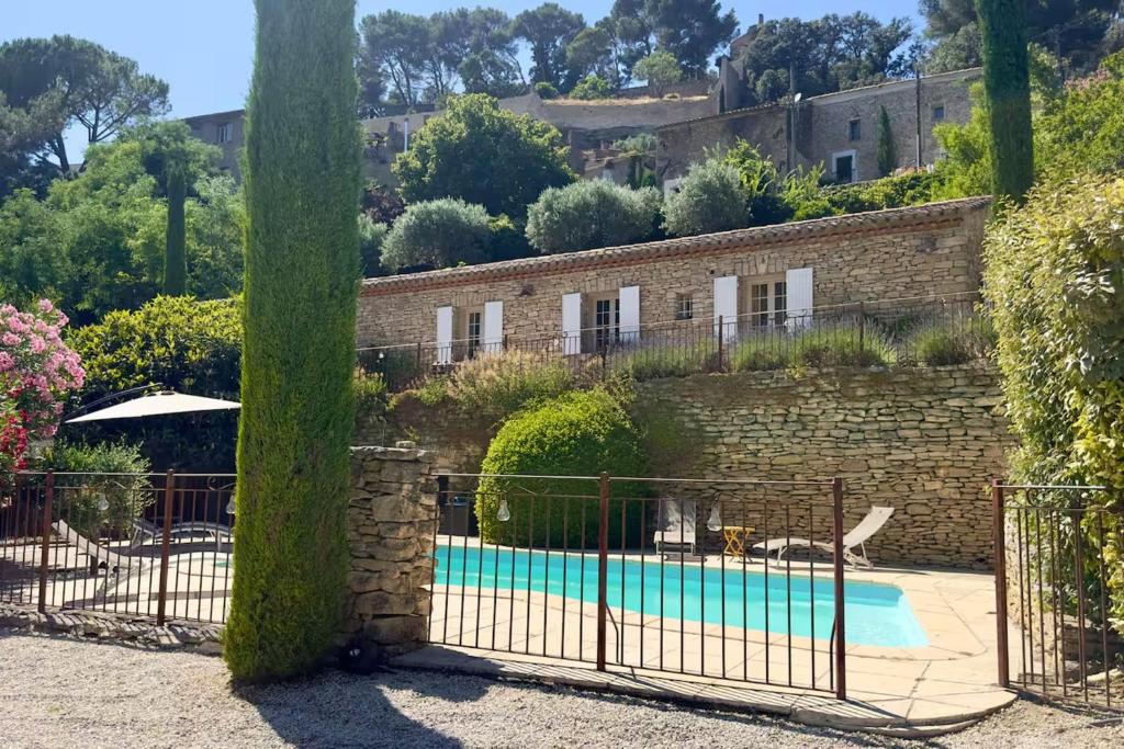 a building with a pool in front of a brick wall at Maison des Cigales a heavenly setting in Saumane-de-Vaucluse