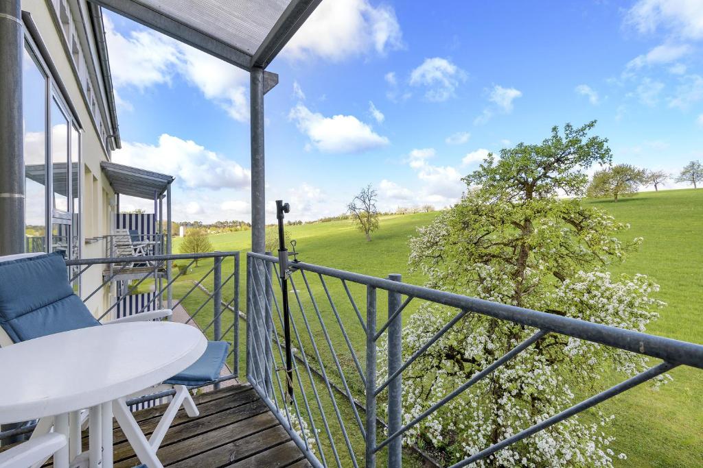 a balcony with a table and chairs and a view of a field at Apartment mit Gartenblick K1 201 in Spalt