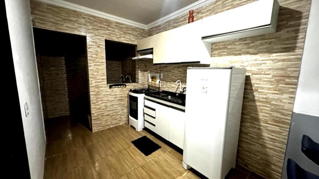 a kitchen with white cabinets and a brick wall at Flat Maracarib um espaço todo seu próximo de tudo in Maragogi