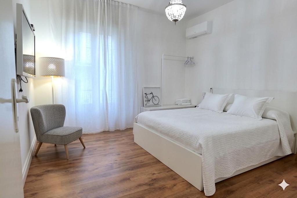 a white bedroom with a bed and a chair at La Casa Della Zia Scicli in Scicli