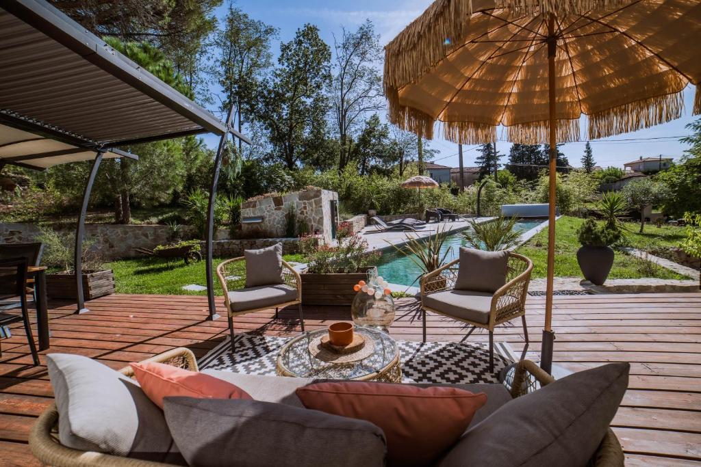 a patio with an umbrella and chairs and a pool at Domaine S&B in Aubenas