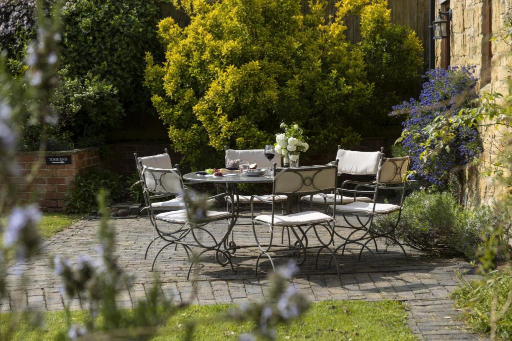 a patio table and chairs in a garden at Norton Subedge Barn in Mickleton