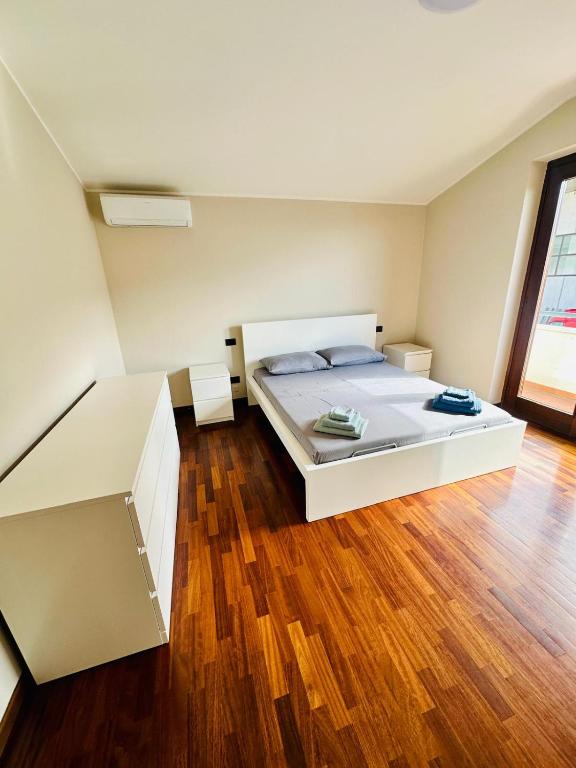a bedroom with a white bed and a wooden floor at Mamisà 4 - appartamenti e camere private con bagno in Schio