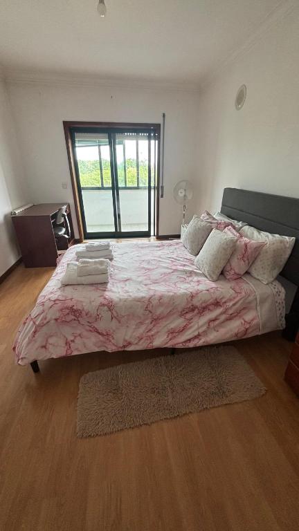 a bedroom with a large bed with a pink blanket at Quarto duplo com varanda no centro de Viseu in Viseu