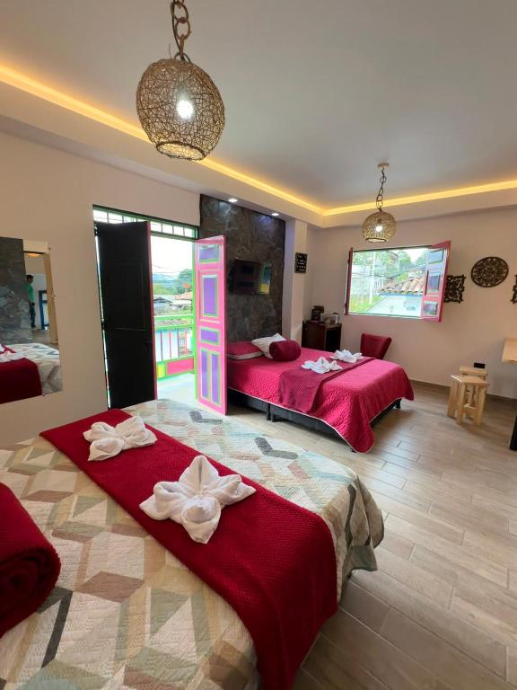 two beds in a room with red sheets at Rincon del descanso in Salento