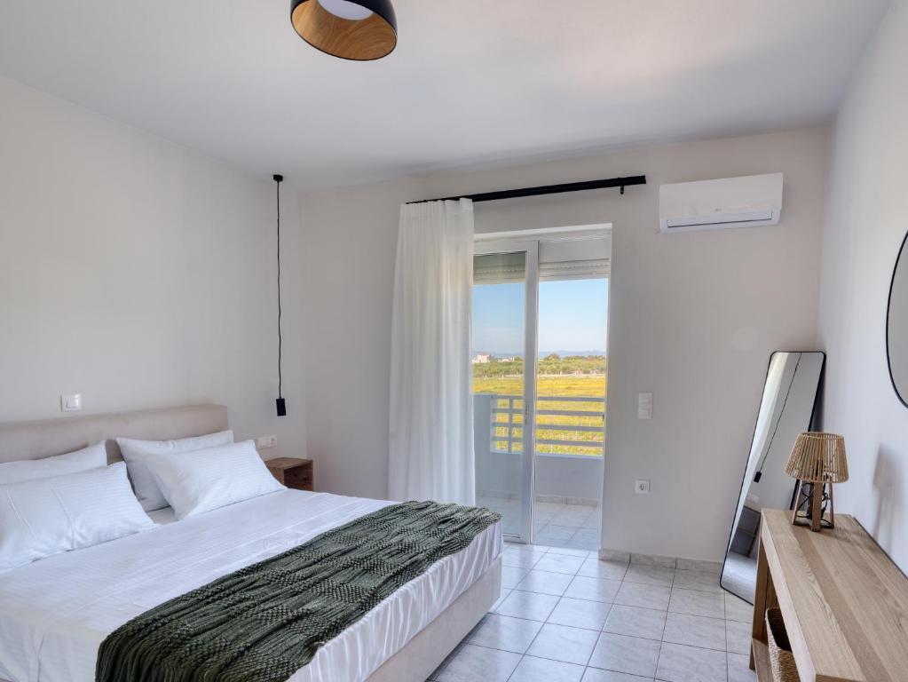 a white bedroom with a bed and a sliding glass door at Aurelea Luxury Apartments in Kos