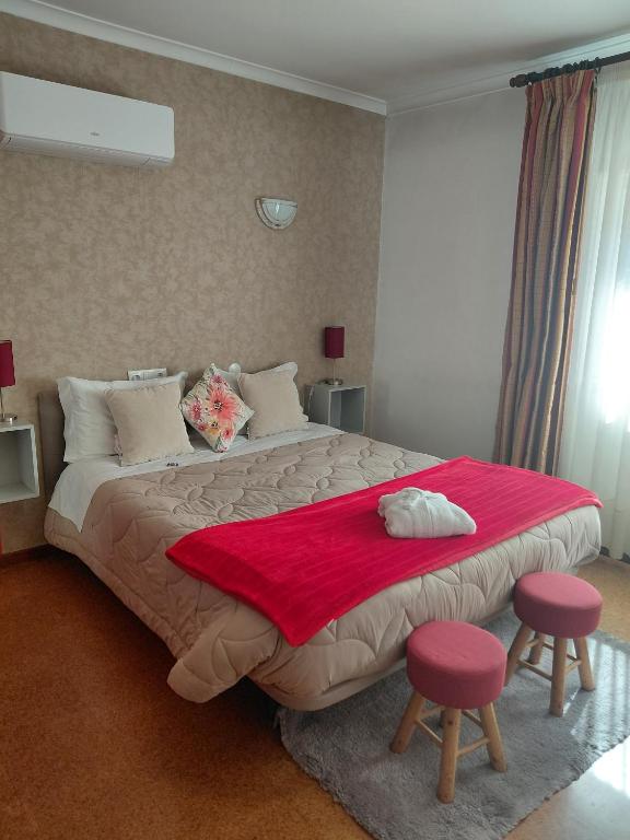 a bedroom with a large bed with two pink stools at Hotel Santa Apolonia in Bragança
