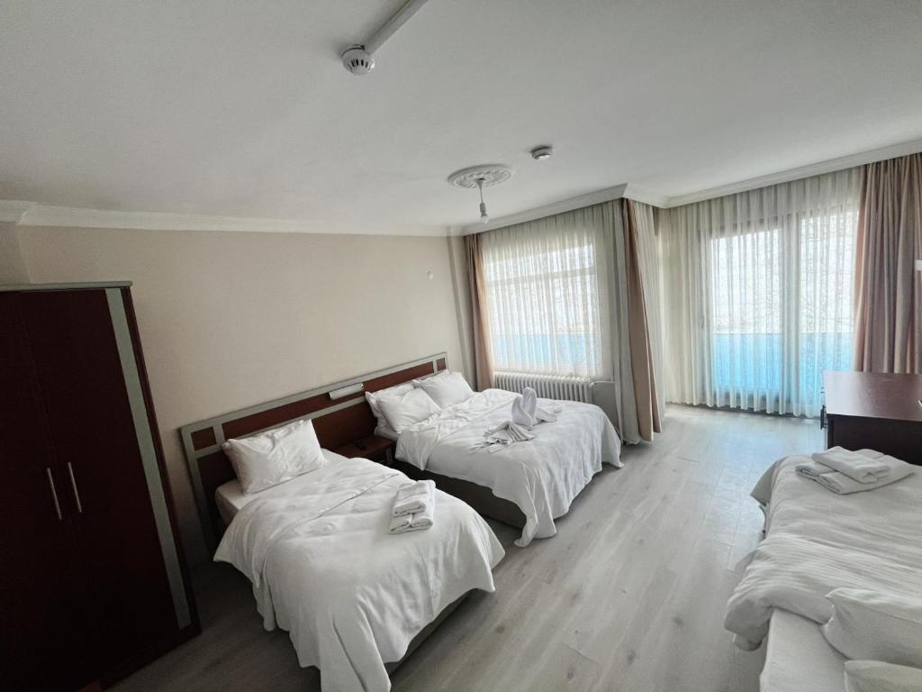 a hotel room with three beds with white sheets at Dolphins Otel in Akçakoca