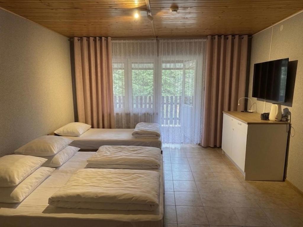 a room with three beds and a television in it at okuninkanoclegi in Okuninka