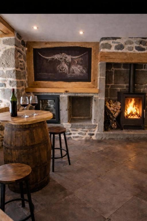 a bar with a fireplace and a table and chairs at Maison en Auvergne - Chez Julien et Stephy in Celles