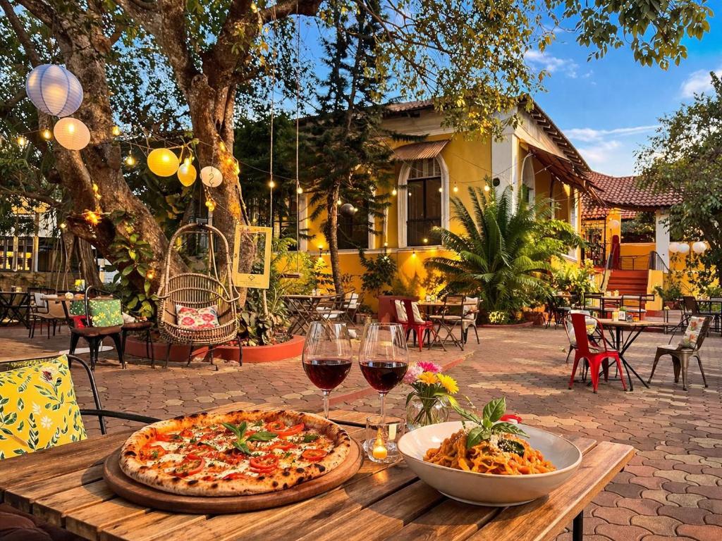 a pizza and wine glasses on a wooden table at Casa Do Leão - Heritage Boutique Stay in Nerul