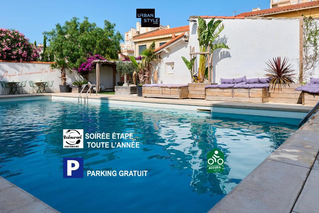 ein Pool mit blauem Wasser vor einem Haus in der Unterkunft Hôtel Les Sables - Urban Style - by Logis Hotels in Canet-en-Roussillon