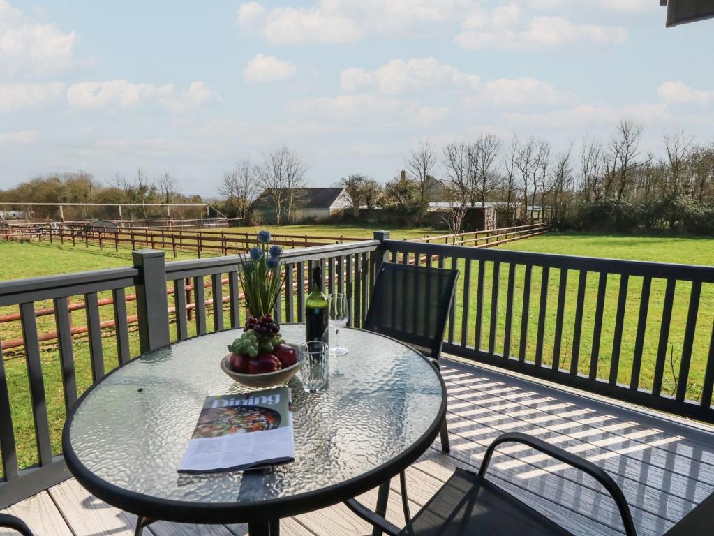 a table with a book and a bottle of wine on a balcony at Grass Roots in Temple Combe