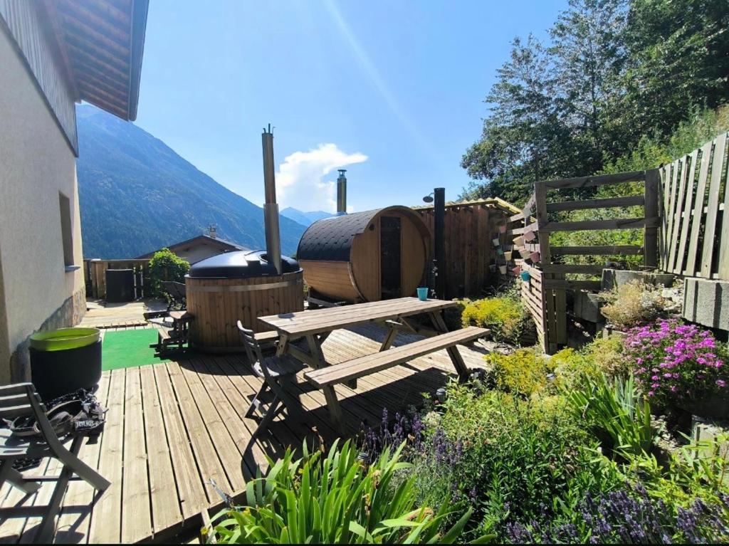 a wooden deck with a picnic table and a grill at La Skibelle Orelle-ValThorens- Sauna & bain nordique in Orelle