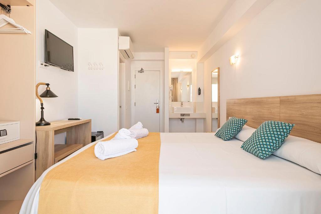 a bedroom with a large bed with blue and white pillows at Suncoast Ibiza Hotel - Adults Only - in Ibiza Town