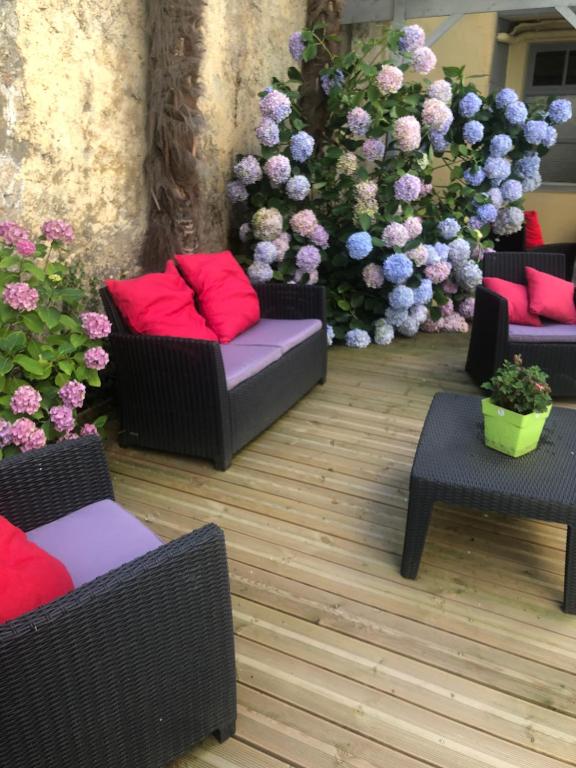 a patio with couches and tables and flowers at Le Béout rez-de-jardin in Lourdes