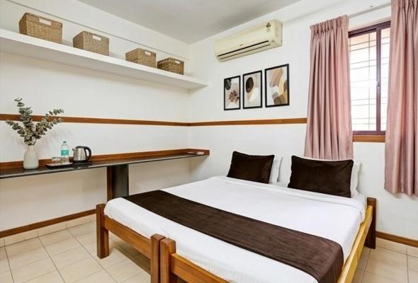 a bedroom with a bed and a desk in it at svnstay in Tirupati