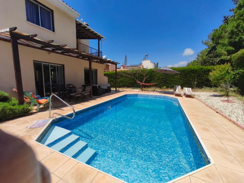 a swimming pool in the backyard of a house at Villa Koralia in Peyia