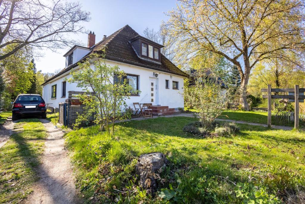 a white house with a car parked in the yard at Ferienwohnung Schack in Hoisdorf