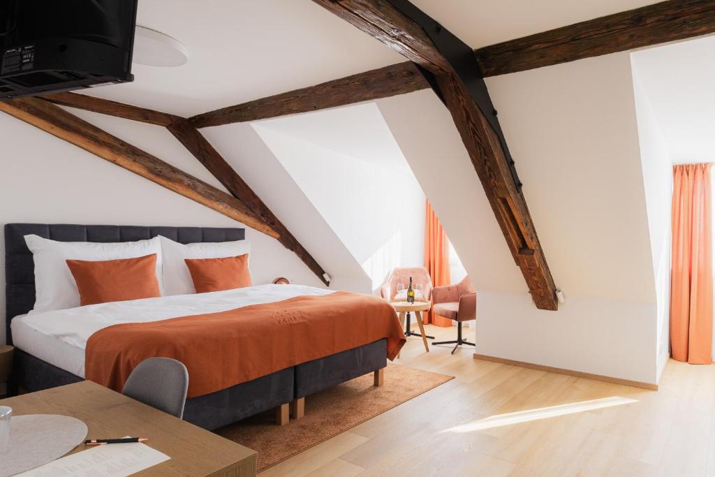 a bedroom with a bed with an orange blanket at Maison Kounic Palace Suites in Slavkov u Brna