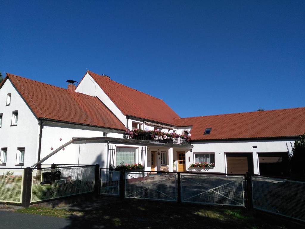 ein weißes Haus mit einem Zaun davor in der Unterkunft Knoblochs Ferienhof in Weißenberg