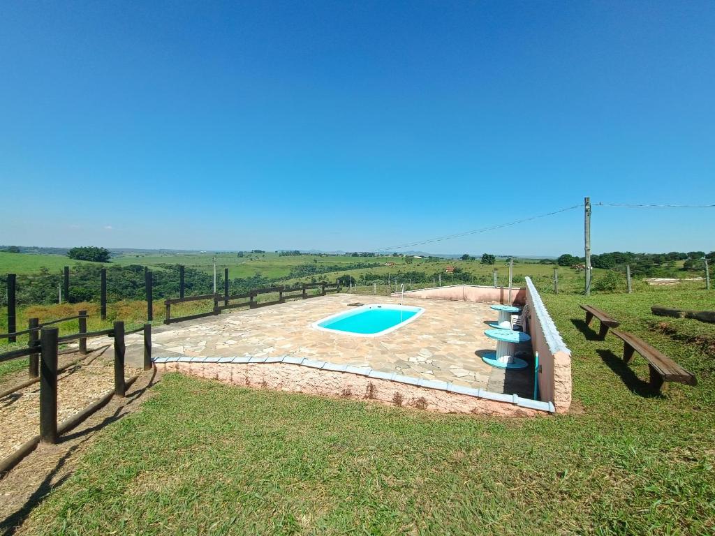 a pool in a field with benches and a fence at Pousada Xodó in São Pedro