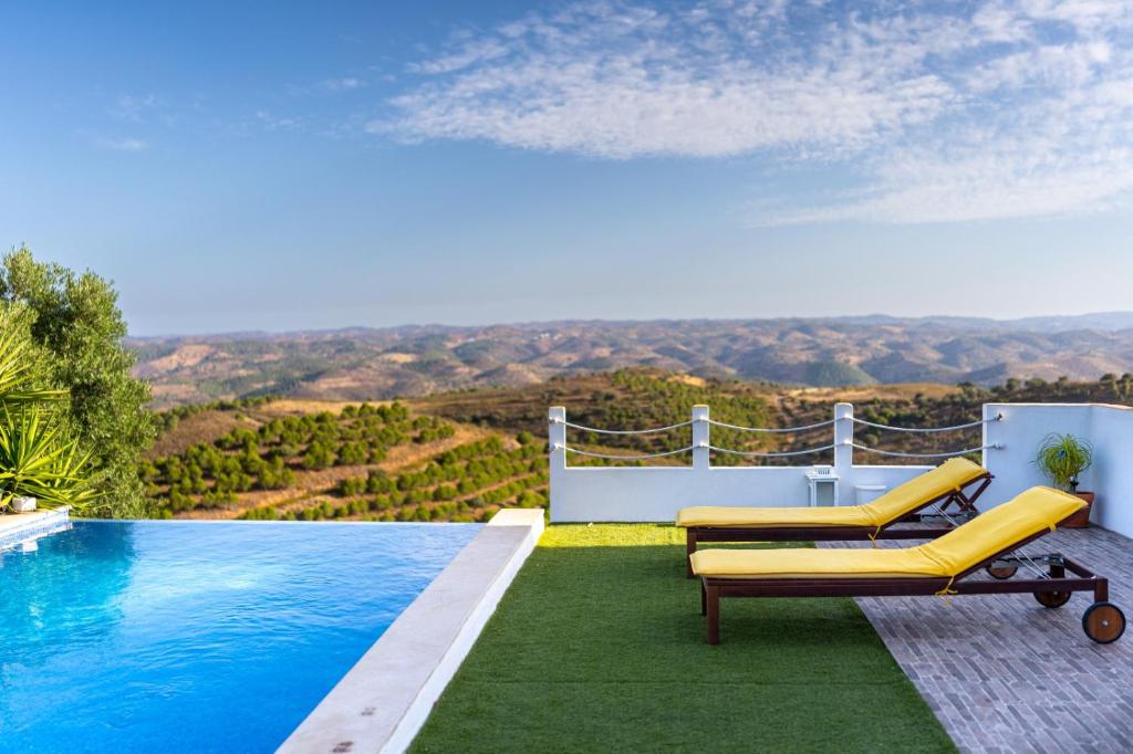 a pool with two yellow lounge chairs next to a pool at Varandas do Vale Furnazinhas in Castro Marim