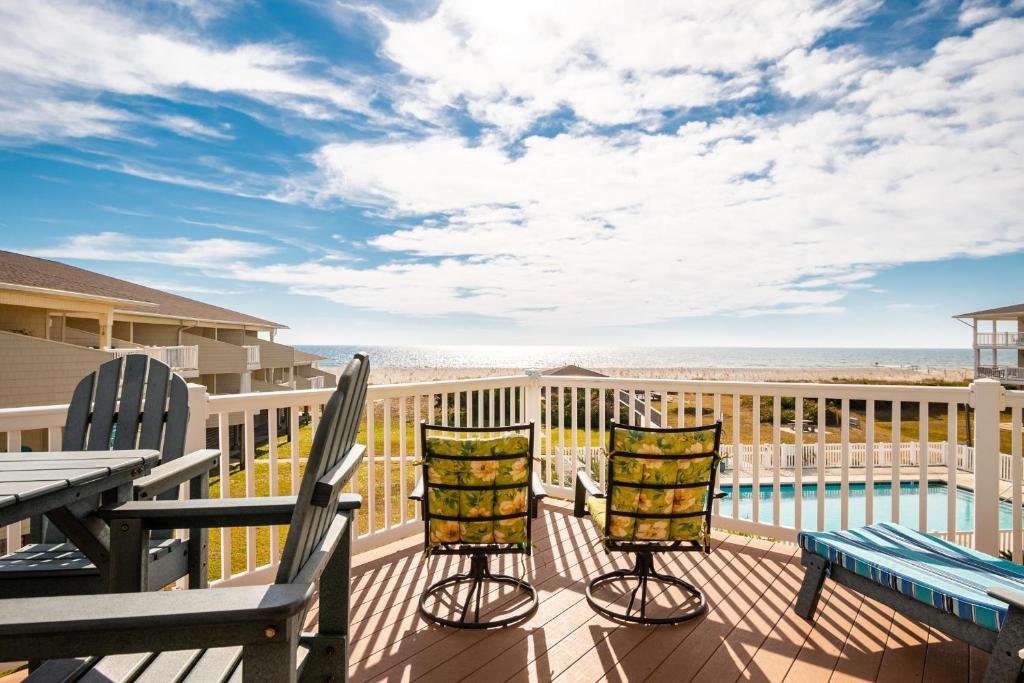 a deck with chairs and a table with a view of the ocean at Fish Tales by Oak Island Accommodations in Oak Island