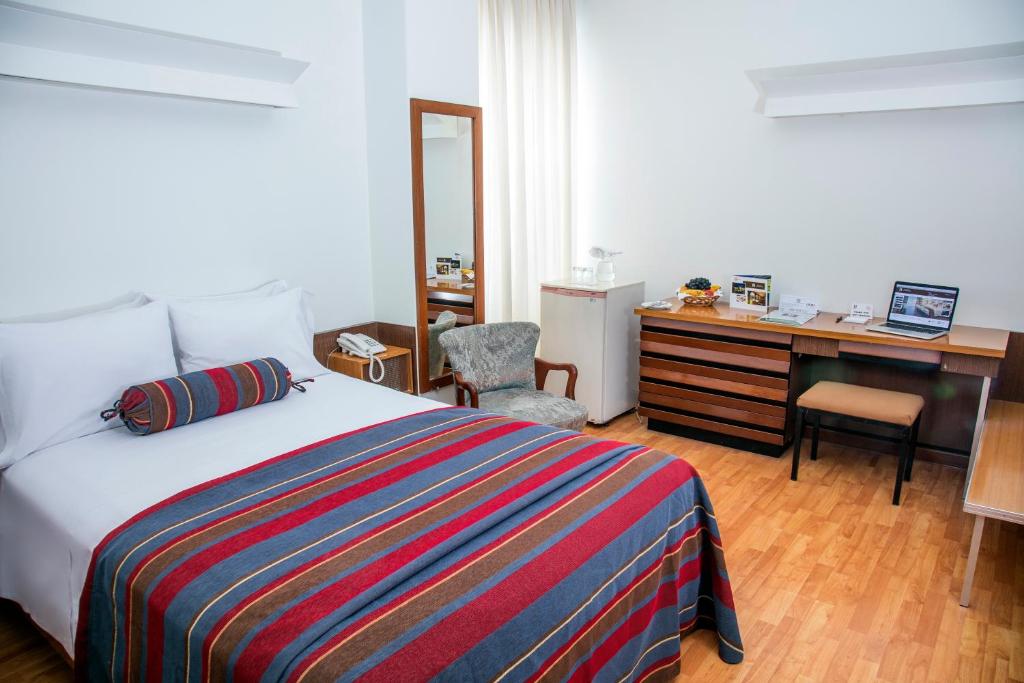 a bedroom with a bed and a desk and a chair at San Agustin Riviera in Lima