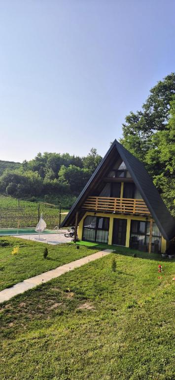 a house with a gambrel roof on top of a field at Vikendica Buzadzija M&N in Piskavica